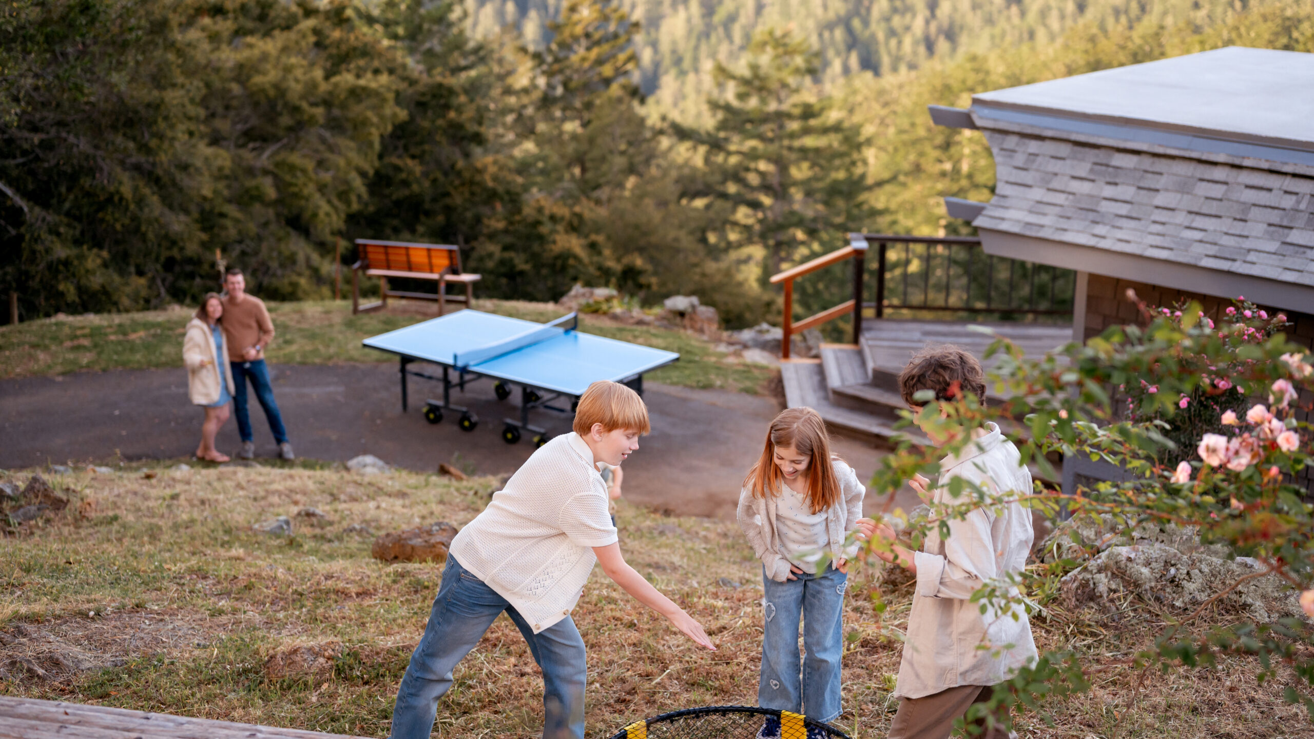 Kids playing spikeball with parents looking in the distance